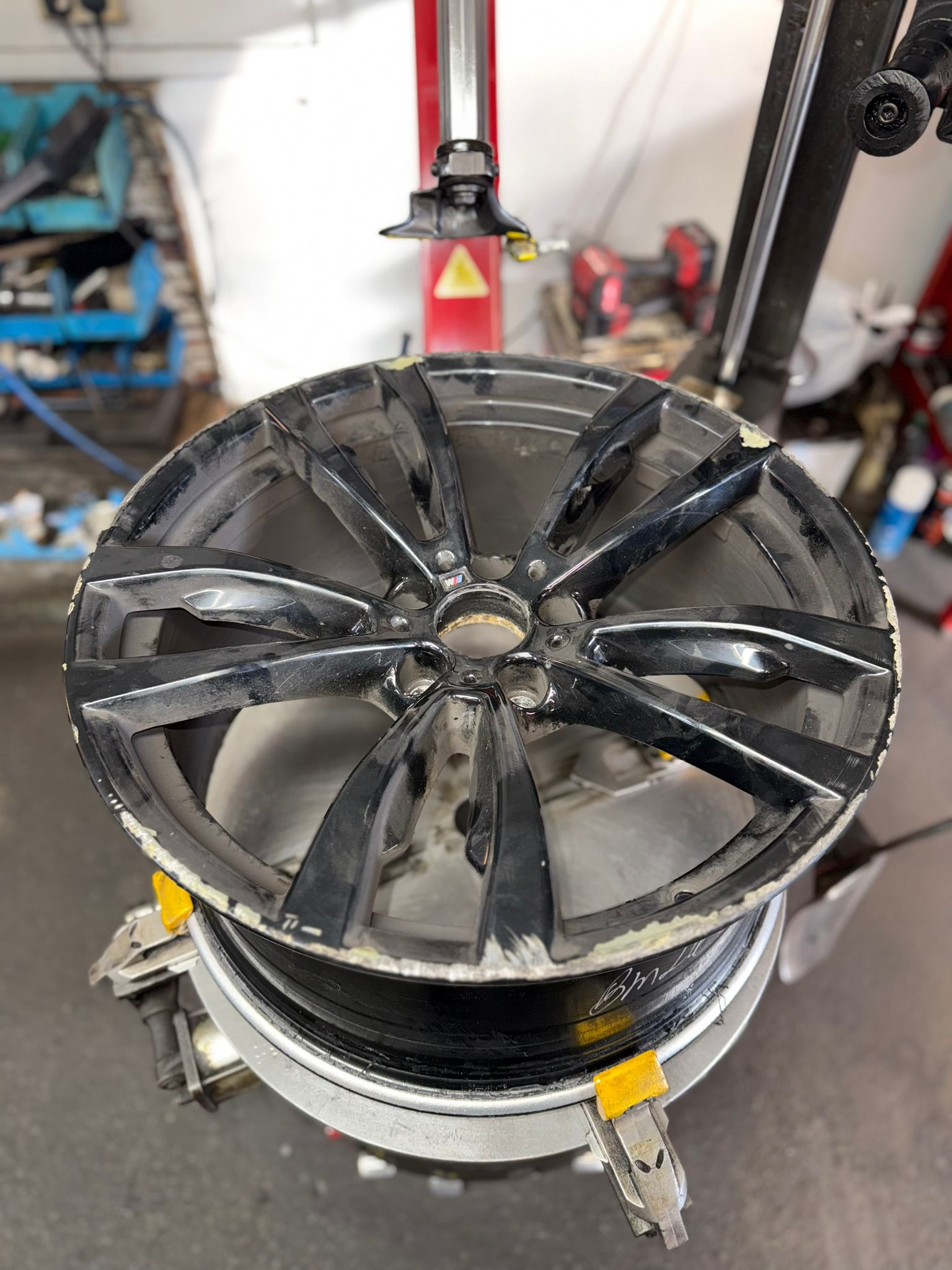 Before — Flaking, kerbed gloss-black wheel stripped right back, repaired and powder-coated to a deep gloss finish. — Burnley