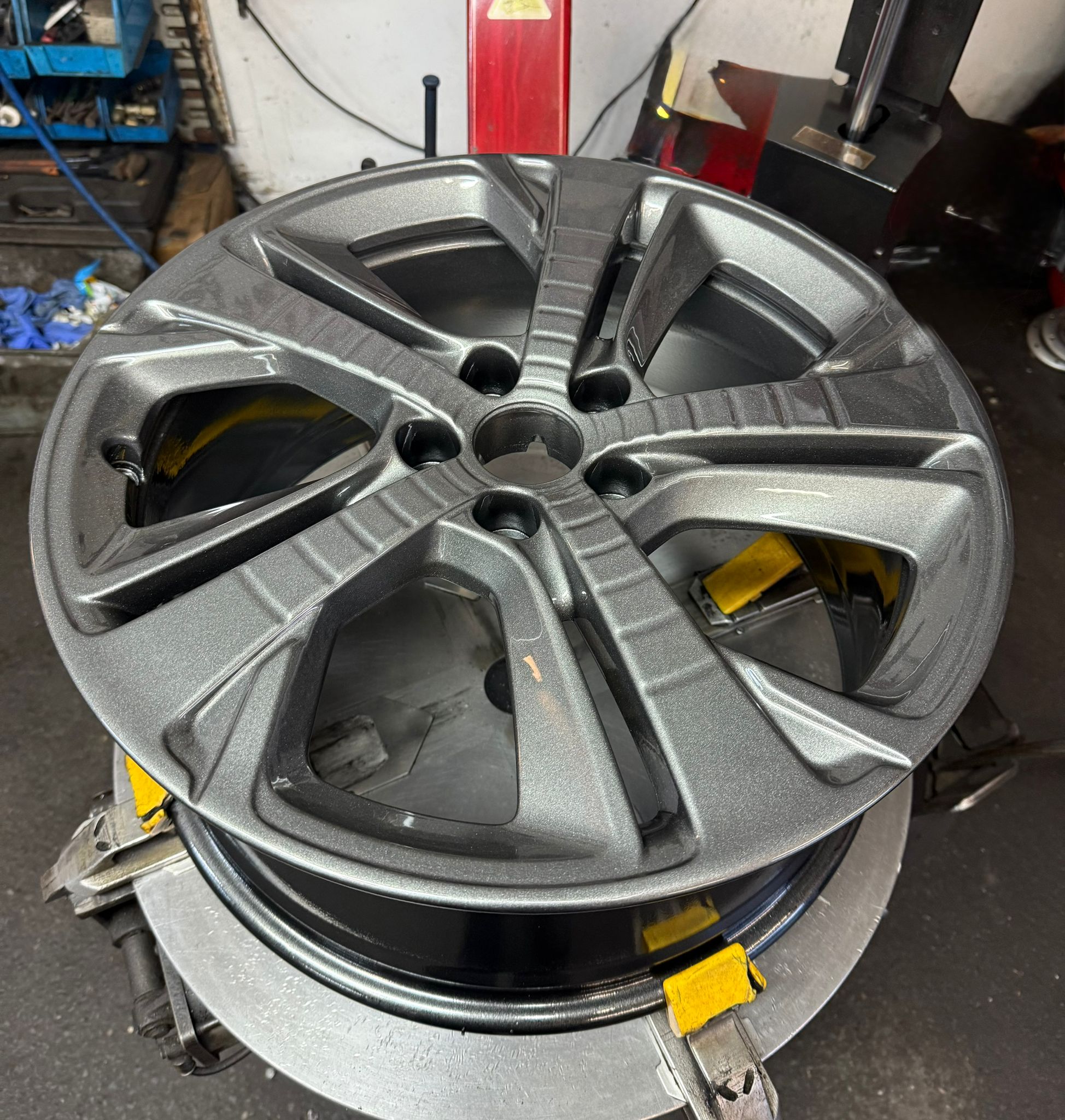 A five-spoke alloy refurbished in a deep gunmetal grey powder coat
